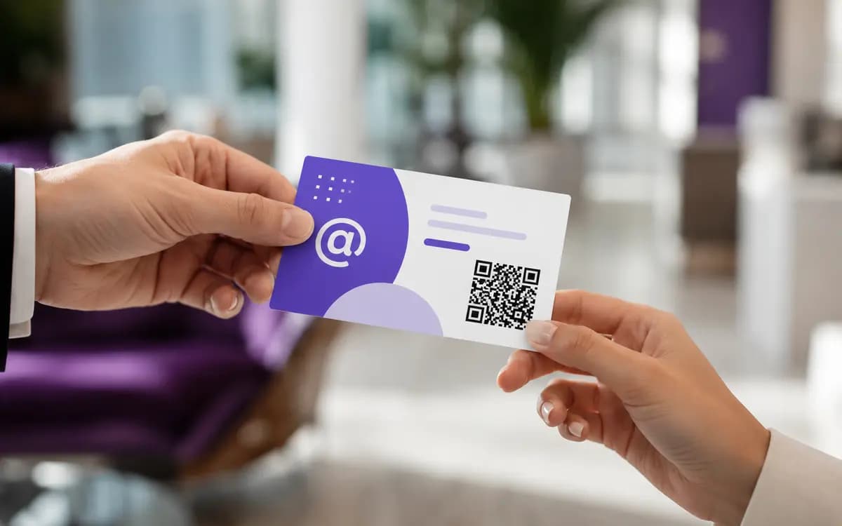 Business card with a QR code on its back, held in a hand